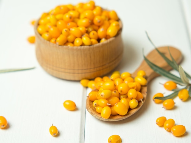 Fresh sea buckthorn berries in a wooden bowl and spoon