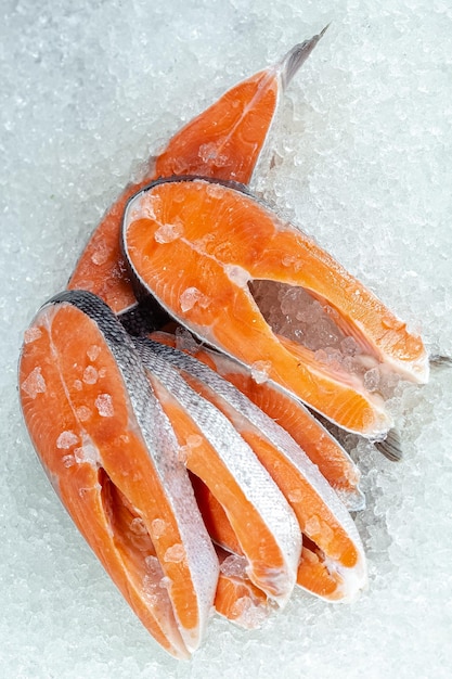 신선한 바다 붉은 물고기는 조각으로 잘리고, 머리, 체리, 레몬 조각 없이 얼음 위에 놓여 있습니다.