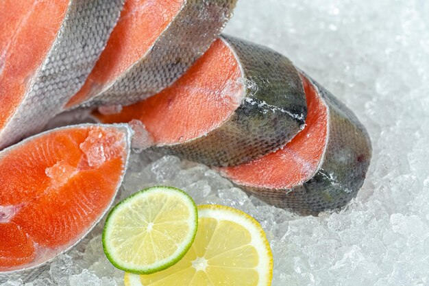 fresh sea ocean red fish is cut into pieces, lies on ice, without a head, cherry, slices of lemon