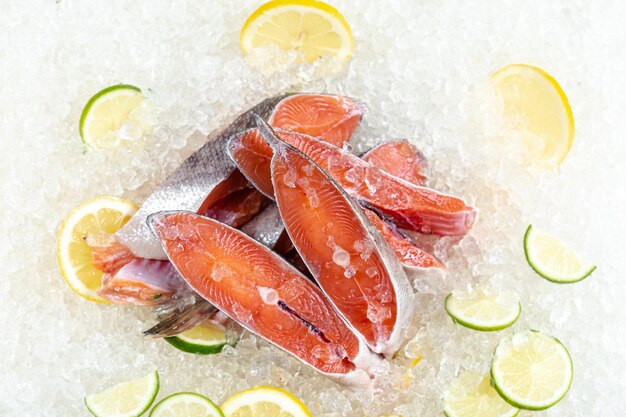 fresh sea ocean red fish sliced in pieces, lying on ice, headless, cherry, sliced lemon and lime