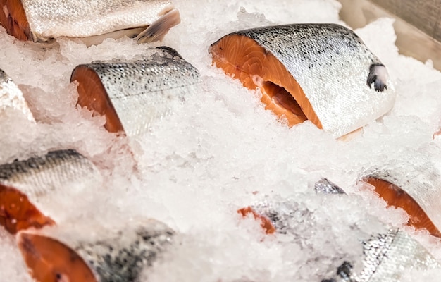 魚市場で砕いた氷の上で新鮮なシーフード。店内の陳列カウンターに冷凍海魚。デザインのための抽象的な食品の背景の概念。サイトのコピースペース