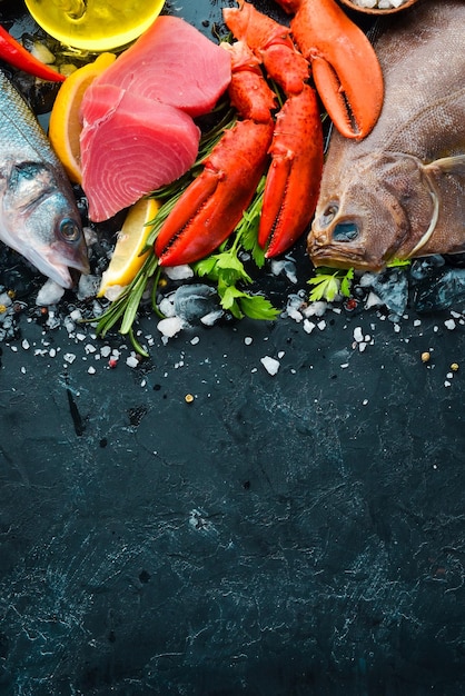 Fresh seafood and fish on black stone background flounder
lobster squid tuna fish top view free copy space