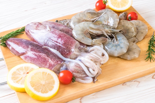 Pesce fresco crudo (gamberetti, calamari) su tavola di legno