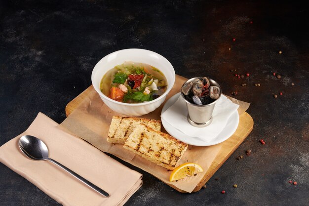 Fresh seafood soup in bowl, dark background