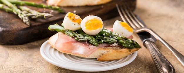 Fresh sendwich with ham, asparagus and quail eggs