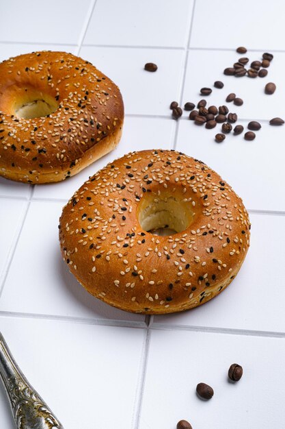 Bagel di sesamo fresco impostato su sfondo di tavolo piastrellato in ceramica bianca