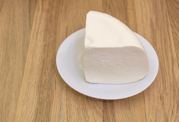 Fresh sheep cheese in a plate on wooden background