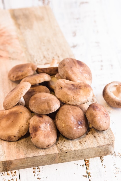 Fresh shiitake in a wooden board over a wooden white table