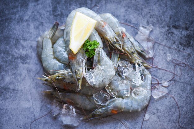 Fresh shrimp prawns at restaurant or seafood market. raw shrimps with herb spices on dark plate