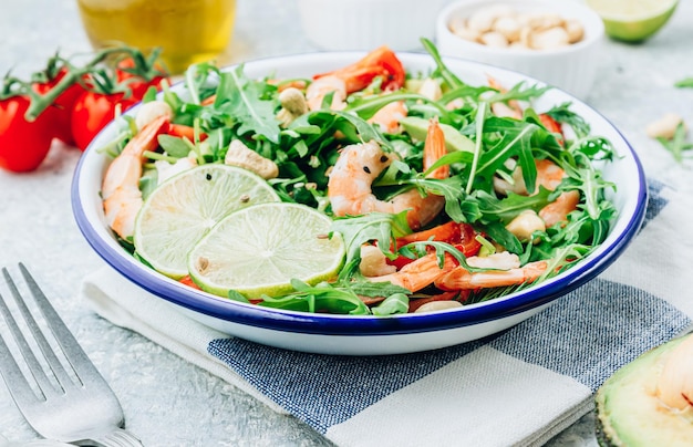 Insalata di gamberi freschi con pomodoro, rucola, avocado e anacardi su sfondo di pietra messa a fuoco selettiva