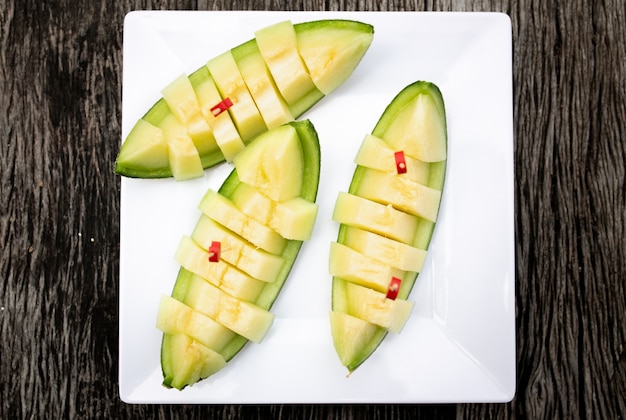 Fresh slice sweet green melon on white crokery put on wooden table.