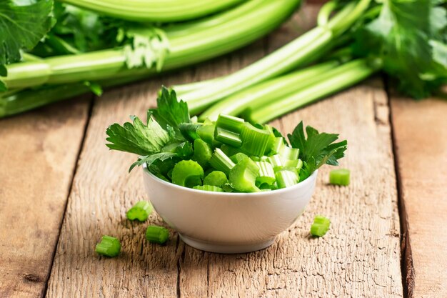 Fresh sliced celery in a white bowl on a vintage wooden background selective focus