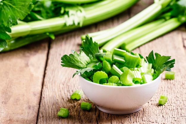 Fresh sliced celery in a white bowl on a vintage wooden background selective focus