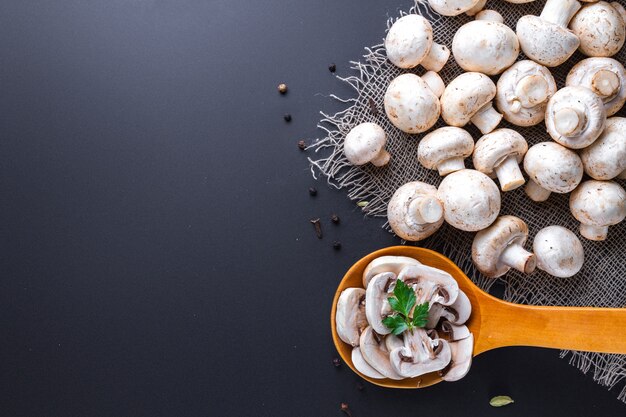 Champignon affettato fresco con prezzemolo in cucchiaio di legno. cucinare deliziosi piatti fatti in casa di funghi bianchi maturi. copia spazio