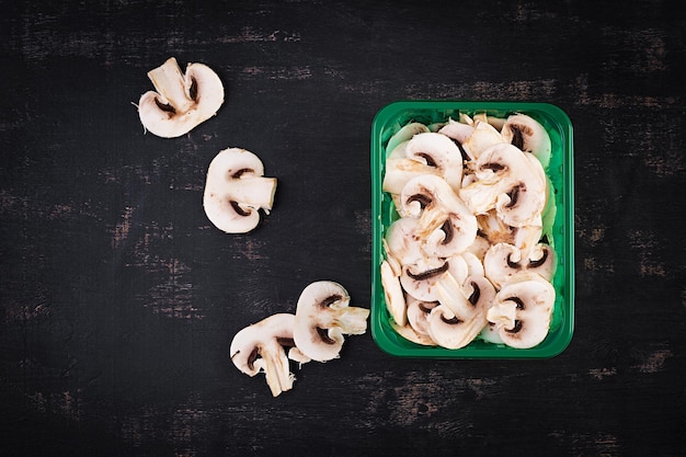 Champignon freschi a fette su sfondo scuro vista dall'alto sopra