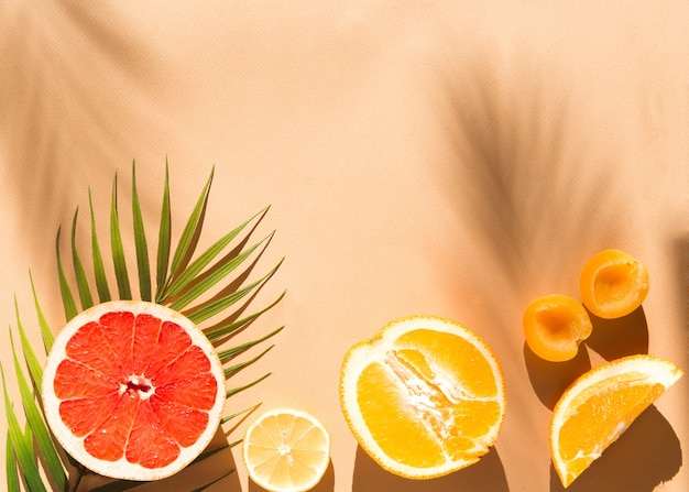 fresh sliced fruits flat lay on beige background at sunlight