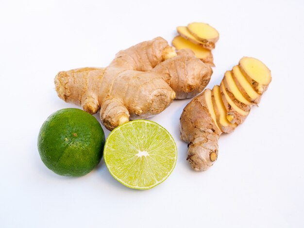 Fresh sliced ​​ginger root and green lemon isolated on white surface.