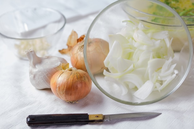 Fresh sliced onions with a glass bowl close-up and a whole onion and garlic