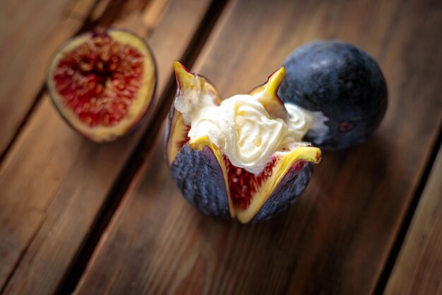 Fresh sliced purple figs with whipped cream on a wooden background from old boards