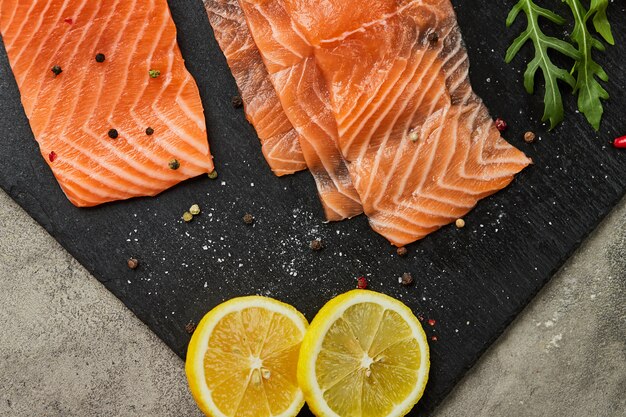 Fresh sliced salmon fillet with arugula, avocado and lemon on slate plate. Wild atlantic fish