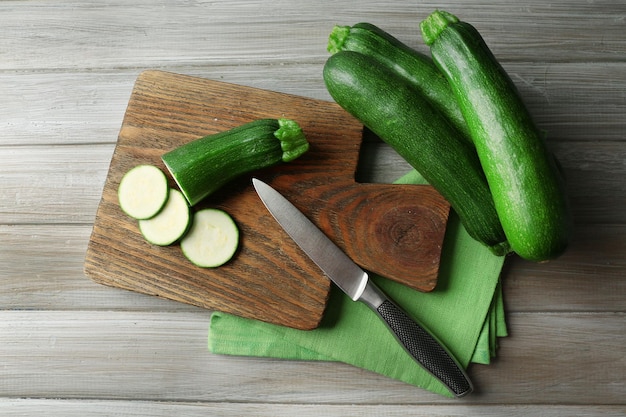 Свежие нарезанные zucchini на режущей доске на деревянном фоне