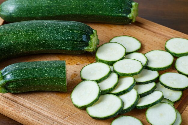 Fresh sliced zucchini on cutting board on wooden background