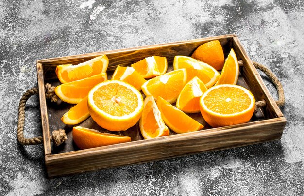 Fresh slices of oranges in a wooden tray on a rustic background