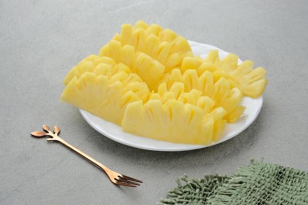 Fresh slices pineapple served in white plate on a grey background Close up Selected focus