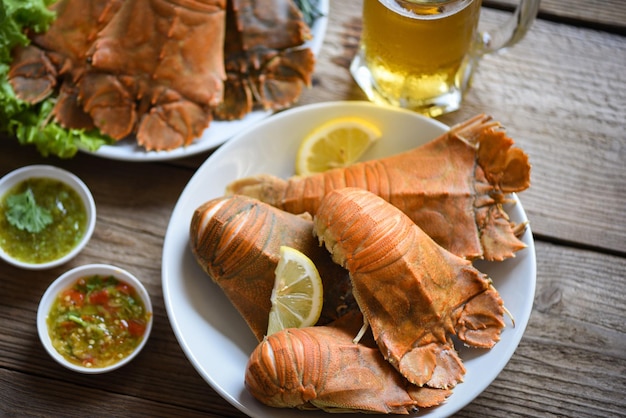 Fresh slipper lobster flathead boiled cooking with parsley rosemary in the restaurant Flathead lobster shrimps served on white plate seafood sauce and mug beer glass Rock Lobster Moreton Bay Bug