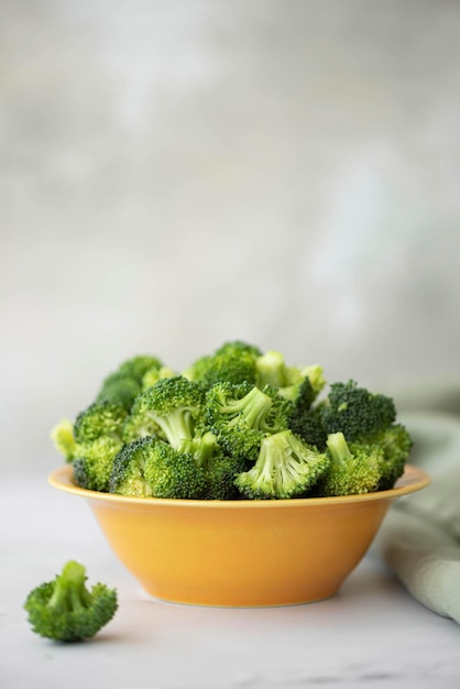 Fresh small broccoli florets in a yellow bowl closeup