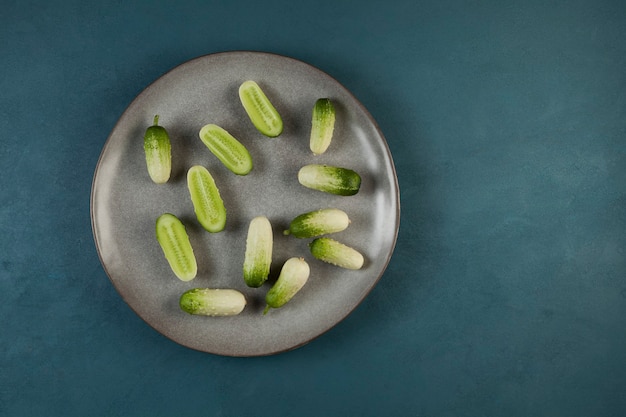 Fresh small cucumbers of unusual color on a gray plate. Top view. Copy space.