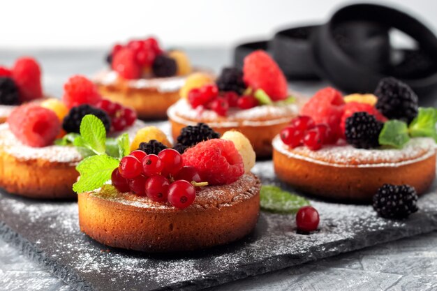 Fresh small homemade fruit pies with raspberries, currants and blackberries on the table