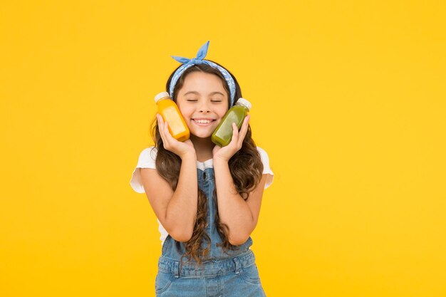 Fresh smoothie. Girl drinking orange fresh juice smoothie. Vegetarian concept. Hand crafted smoothie recipe. Fruit energy. Smiling kid hold smoothie bottles. Healthy food. Vitamin nutrition.