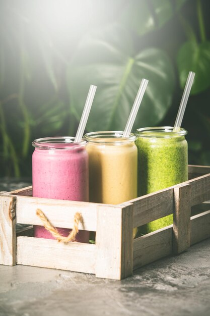 Fresh smoothies on tropical background close up