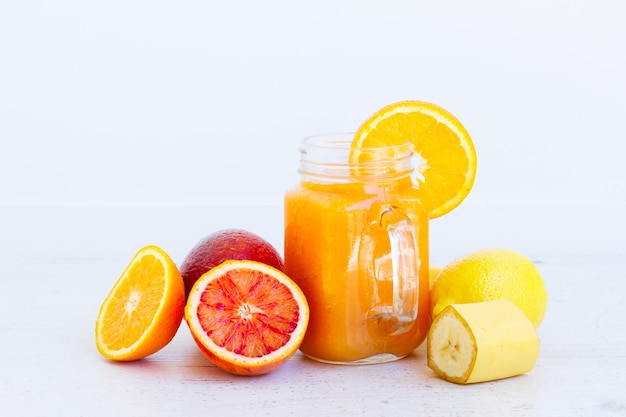 Fresh smoothy orange healthy drink in glass jars with ingredients