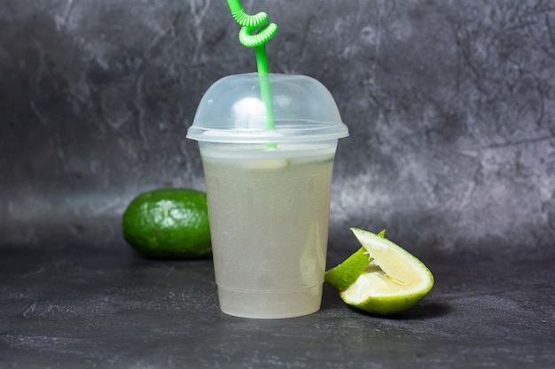 Fresh Soda Lemonade drink with lemon slice and straw served in disposable cup isolated on grey