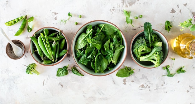 Fresh spinach leaves green peas broccoli in a bowl top view