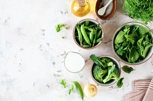 Fresh spinach leaves green peas broccoli in a bowl top view