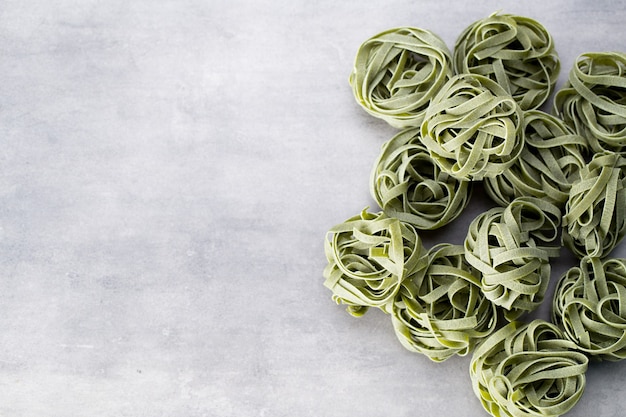 Fresh spinach with green pasta on a gray background.