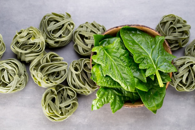 Foto spinaci freschi con pasta verde su sfondo grigio