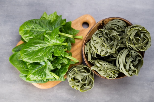 Spinaci freschi con pasta verde su un grigio.