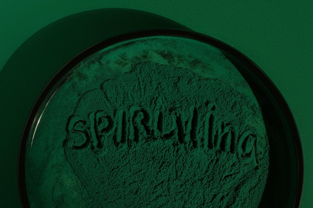 Fresh spirulina algae powder on green background Spirulina lettering closeup organic spirulina powder