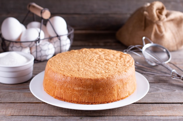 Fresh sponge cake on a white plate on a wooden table. Chiffon biscuit for cake, selective focus
