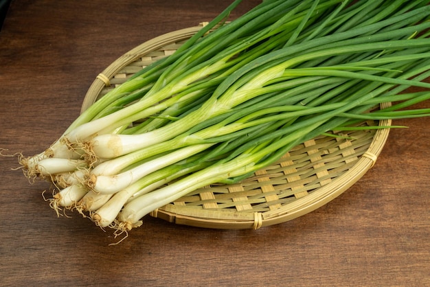 Fresh spring onion in bamboo basket on wooden background