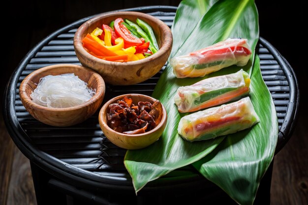 Fresh spring rolls with ingredients on black table