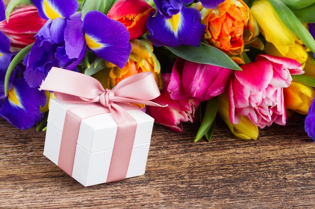 Fresh spring tulips and irises on wooden with gift box