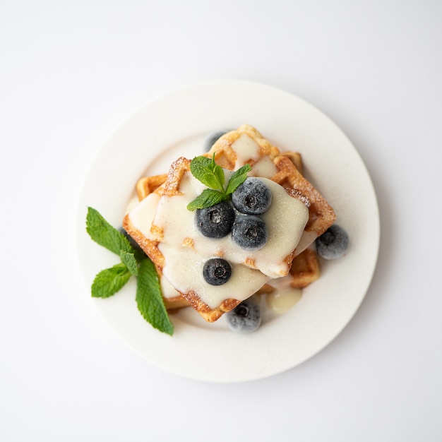 Fresh square waffles with sauce, blueberries and mint leaves