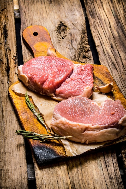 Fresh steaks on an old wooden Board on wooden background