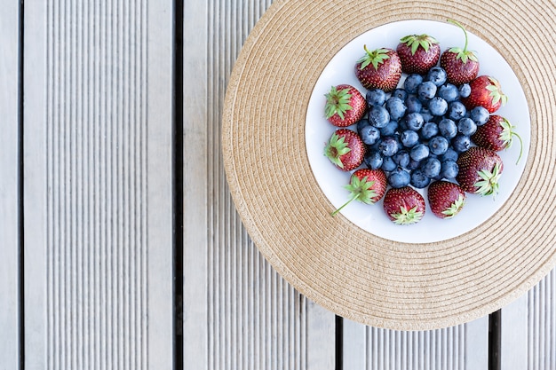 Photo fresh strawberries and blueberries lie in a plate