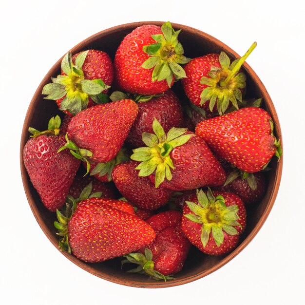 Fresh strawberries in a bowl isolated on white background. Top view.